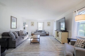 Un salon comprenant un canapé, une table basse, un téléviseur et un meuble.