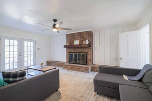 A living room with a fireplace, a ceiling fan, and a sofa. - Sleeps 18 Riverfront Getaway with Game Room & Deck (Valdosta)