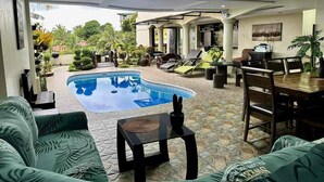 A pool area with a bar and seating, surrounded by greenery.