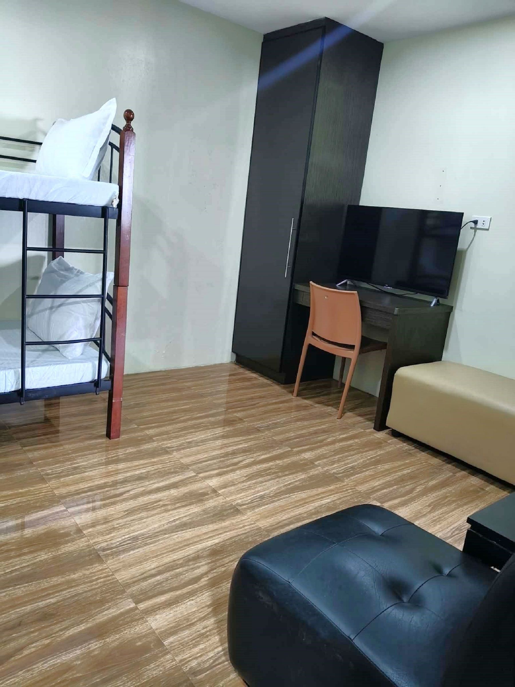 Una habitación con una cama nido, un escritorio, un televisor y un sofá.