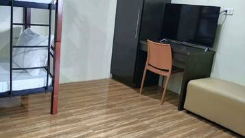 Una habitación con una cama nido, un escritorio, un televisor y un sofá.
