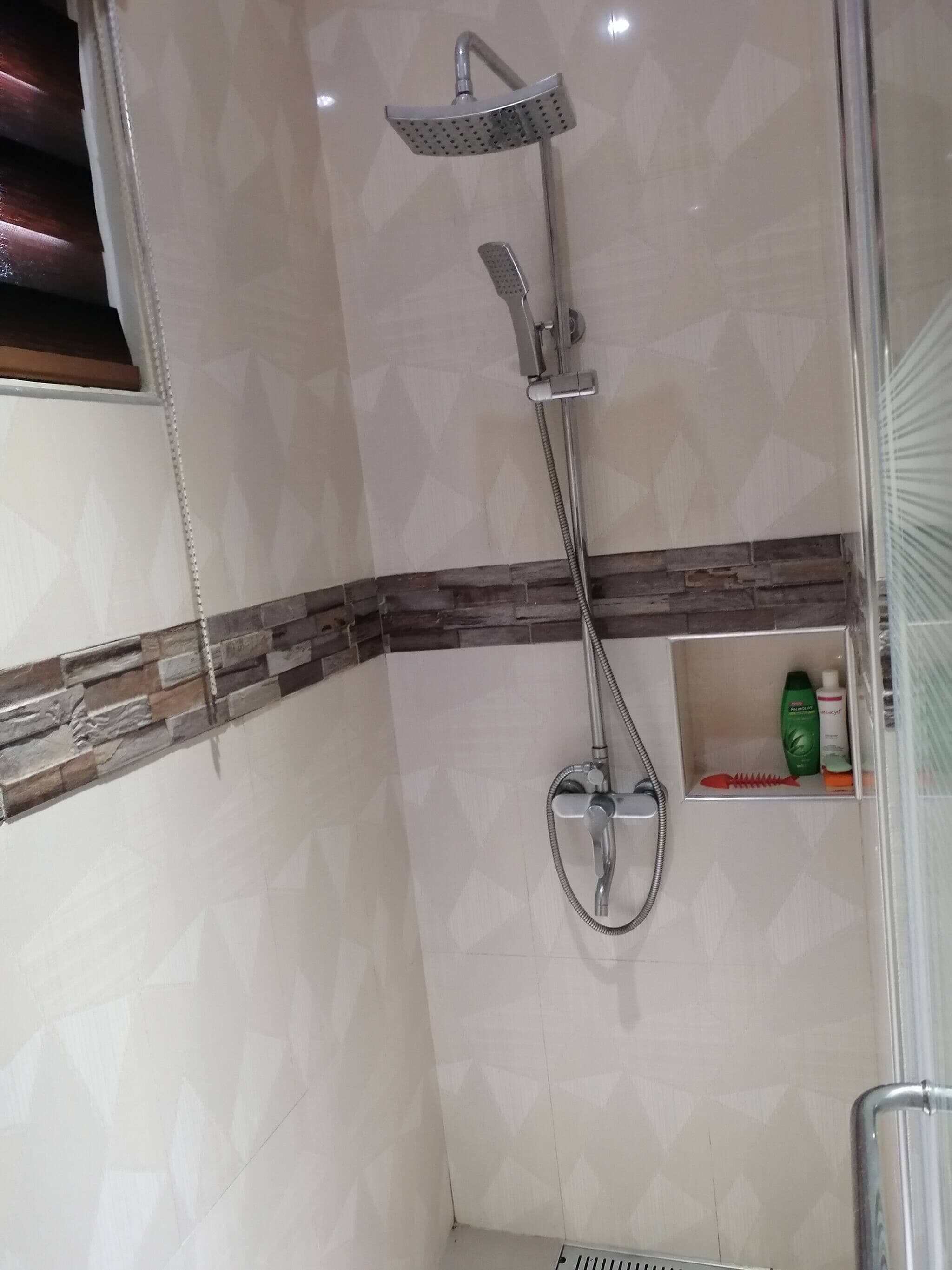 A shower with a handheld showerhead and a wall-mounted rain showerhead.
