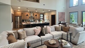 A spacious living area with a large sectional sofa, a coffee table, and a kitchen in the background. - My Place in Powder House Pass, Paved Roads, AC, Hot Tub! (Lead)