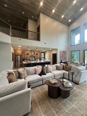 A spacious living area with a large sectional sofa, a coffee table, and a kitchen in the background. - My Place in Powder House Pass, Paved Roads, AC, Hot Tub! (Lead)