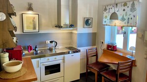 A compact kitchen with a built-in oven, a coffee maker, and a small dining table with chairs. - Tuscan flair in the west of Dresden, not far from Nice in Saxony - Radebeul (Dresden)
