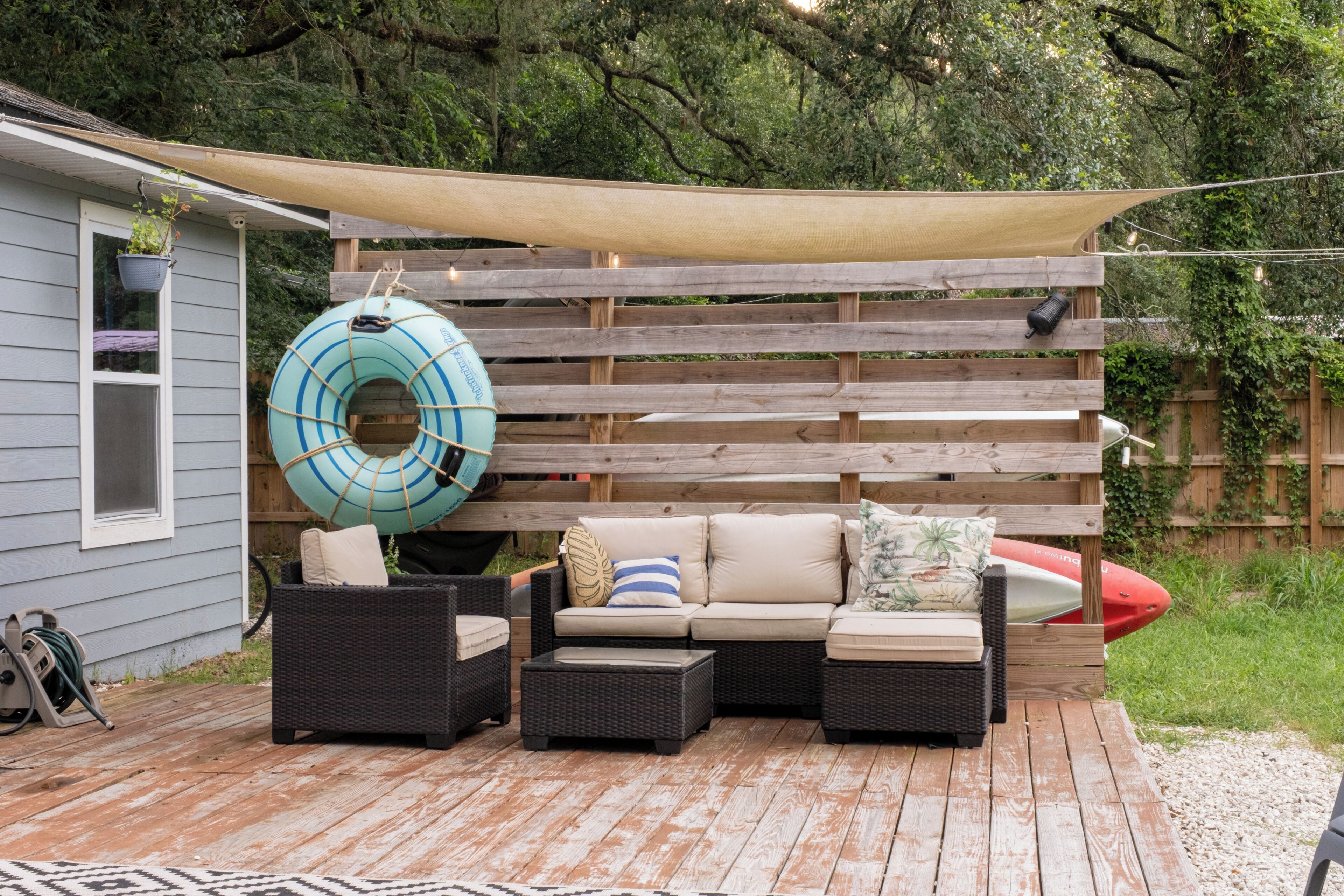 A wooden deck with outdoor furniture, a floating ring, and a canopy.