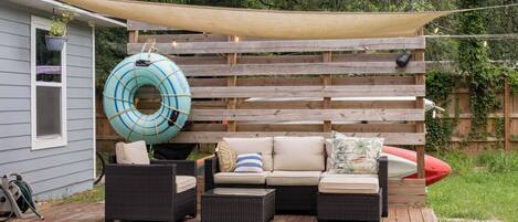 A wooden deck with outdoor furniture, a floating ring, and a canopy.
