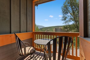 A balcony with a table and two chairs, overlooking a mountainous landscape. - Spacious Wildernest Retreat with Private Hot Tub (Silverthorne)