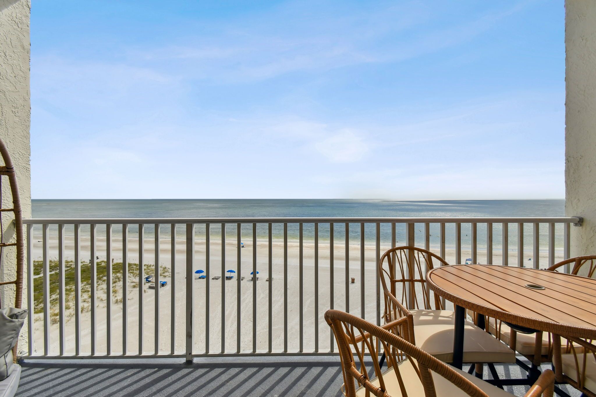Ein Balkon mit Blick auf den Strand, ein Tisch und Stühle.