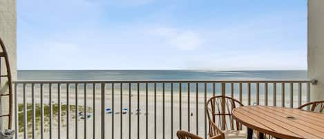 En balkon med udsigt over stranden, et bord og stole.