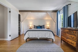 A bedroom with a bed, bedside tables, a dresser, and a patterned rug.