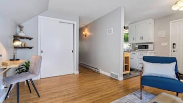A modern apartment with a dining area, a blue sofa, a kitchen, and a white door.