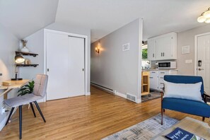Un appartement moderne comprenant un coin repas, un canapé bleu, une cuisine et une porte blanche.