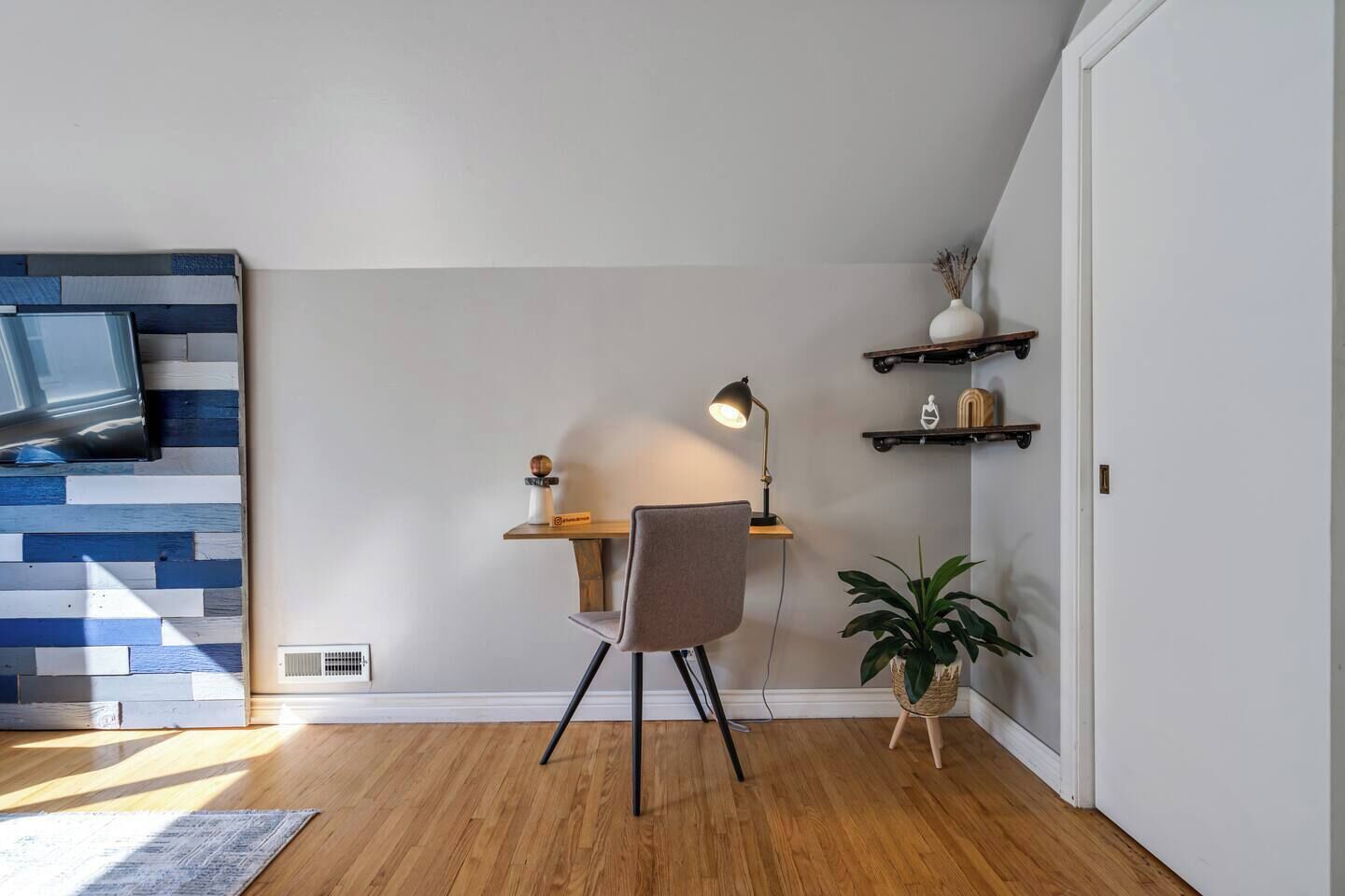 Een moderne kantoorruimte met bureau, stoel, lamp en een schapunit.