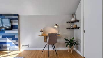 A modern office space with a desk, chair, lamp, and shelving unit.