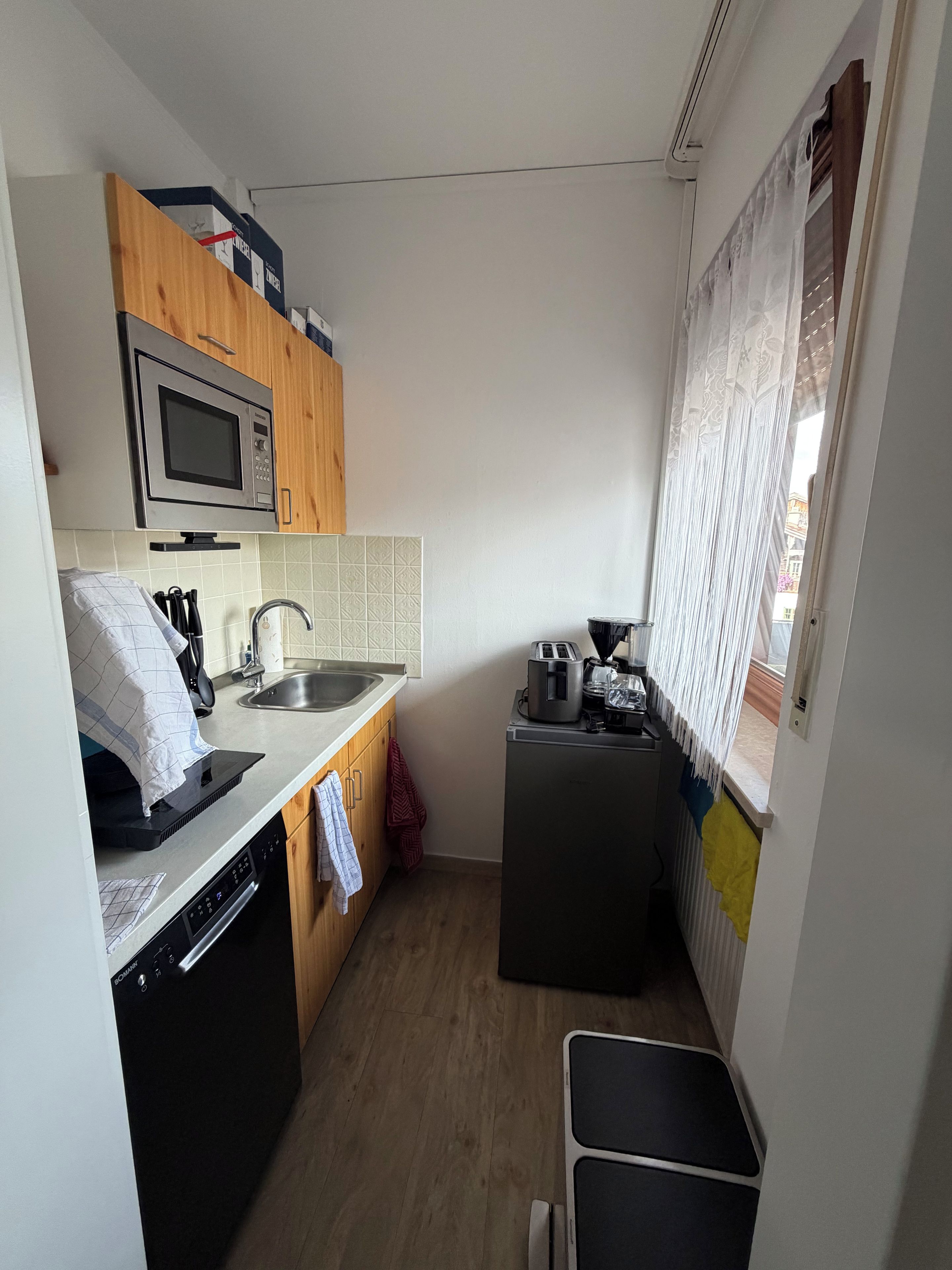 A compact kitchen with a microwave, toaster, and dishwasher.
