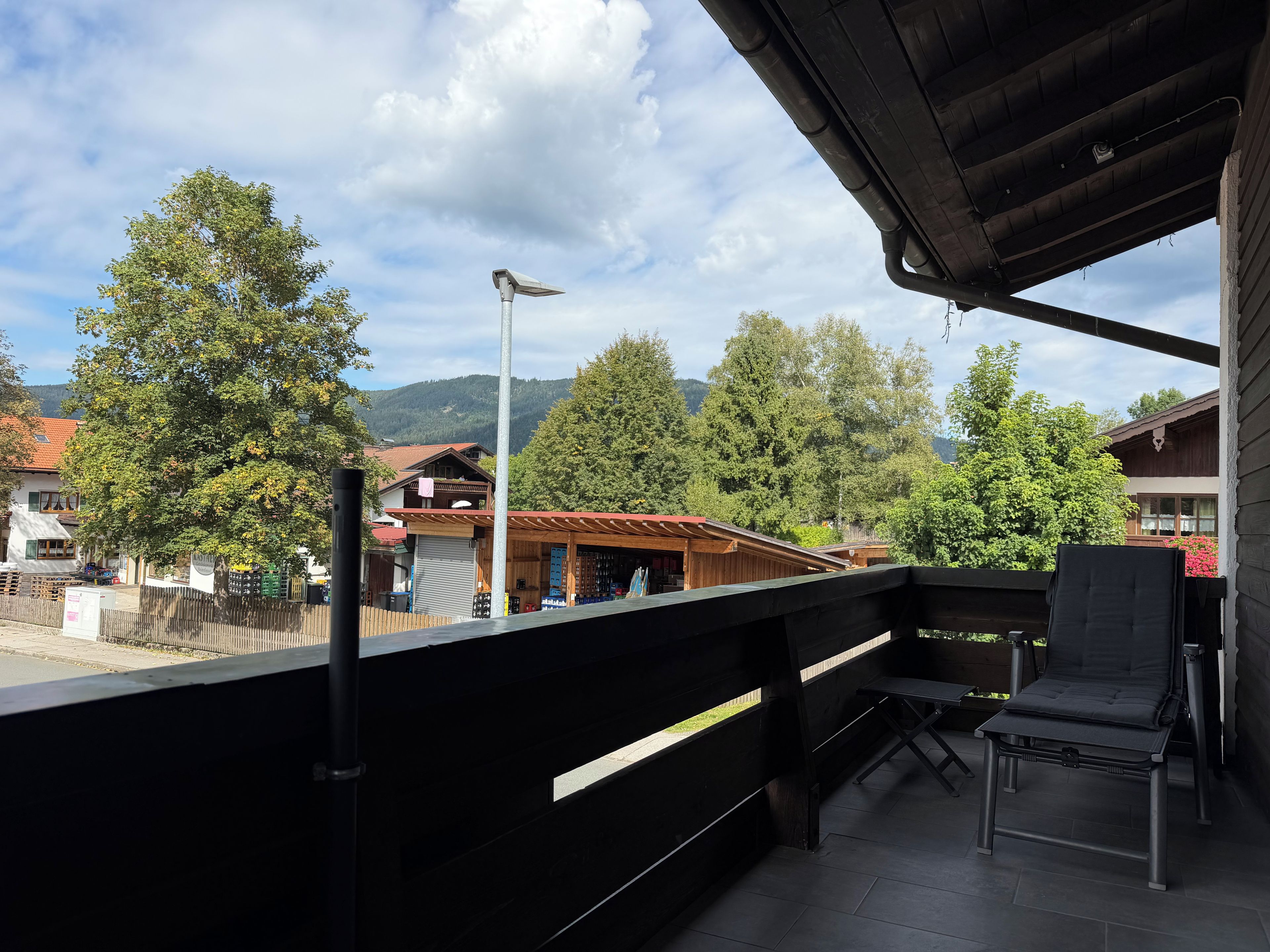 Ein Balkon mit Blick auf eine Stadt, ein Holzgebäude und eine Straßenlaterne.