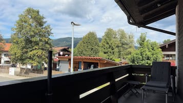 Ein Balkon mit Blick auf eine Stadt, ein Holzgebäude und eine Straßenlaterne.