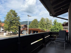 A balcony with a view of a town, a wooden building, and a street lamp.