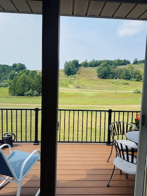 A deck with a view of a grassy field and trees. - 4BR, 4 full bathroom condo, with community pool. Near Lake Michigan. (Cedar)