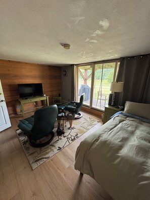 A room with a bed, a TV, a chair, a table, and a window with curtains. - 4BR, 4 full bathroom condo, with community pool. Near Lake Michigan. (Cedar)