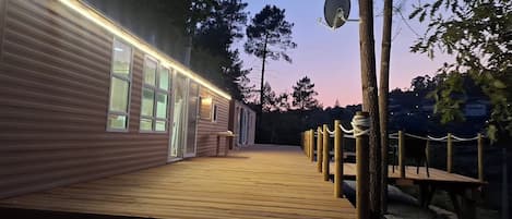Une terrasse en bois menant à un bâtiment doté de grandes fenêtres et d’une antenne parabolique.
