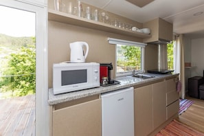 A modern kitchen with a microwave, coffee maker, and a sink.