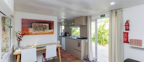 Cocina compacta con comedor, extintor y vista a espacios verdes.