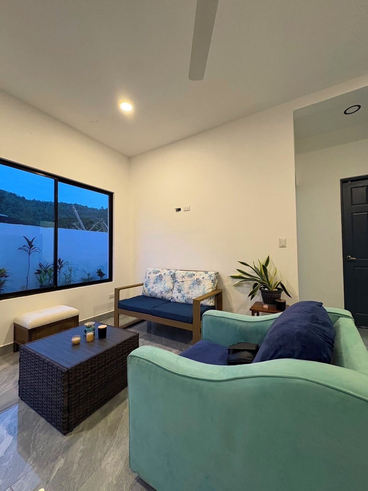 A modern living room with a large window, a sofa, a chair, and a coffee table.