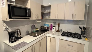 A compact kitchen with a microwave, coffee maker, sink, and a gas stove. - Vacation home with a private pool and close to the beach (Jacó)