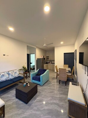 A modern living room with a sofa, armchair, coffee table, and dining area. - Vacation home with a private pool and close to the beach (Jacó)