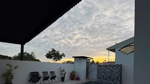 An outdoor swimming pool with a covered seating area, potted plants, and a stone wall. - Vacation home with a private pool and close to the beach (Jacó)