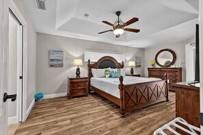 A bedroom with a wooden bed, nightstands, a ceiling fan, and a dresser. - Sea Your Escape | Pool, Game Room & Lanai | Palm Coast Near Flagler Beach (Palm Coast)