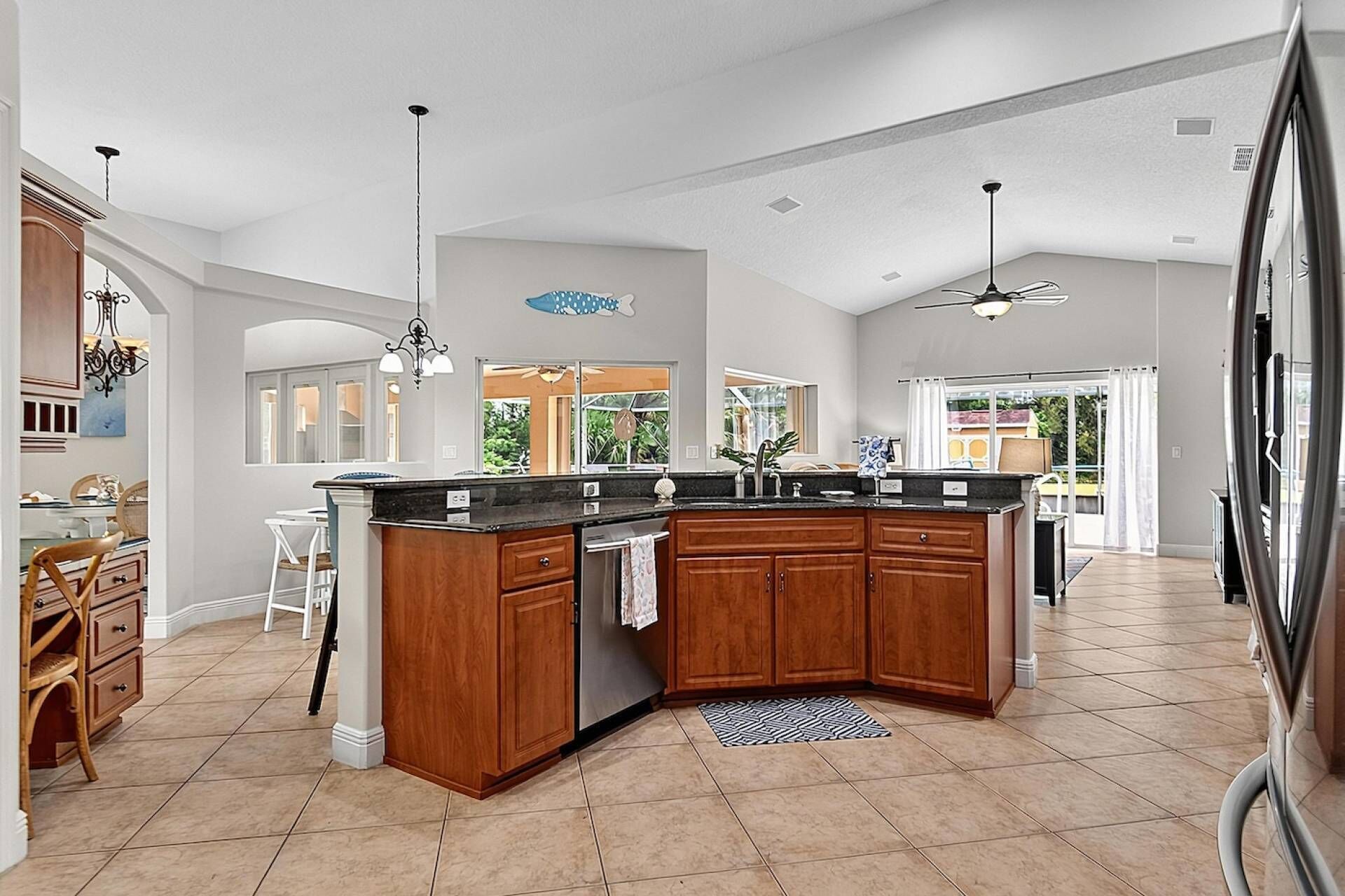 A spacious kitchen with a large island, wooden cabinets, and a view to the outside.