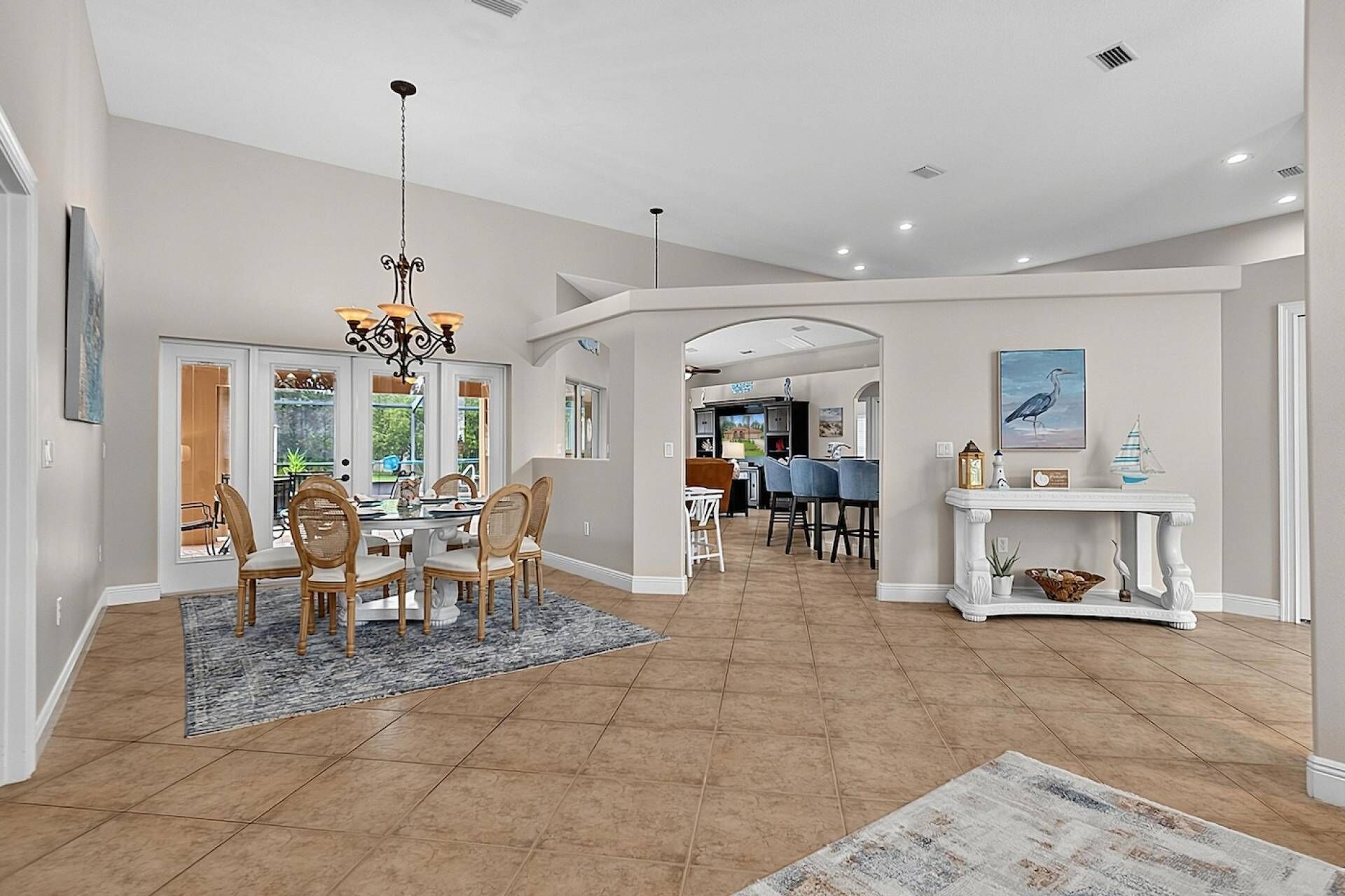 A spacious living area with a dining table, chairs, a chandelier, and a fireplace.