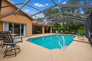 A covered swimming pool with lounge chairs and a patio area. - Sea Your Escape | Pool, Game Room & Lanai | Palm Coast Near Flagler Beach (Palm Coast)