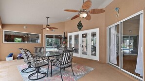 A dining area with a table and chairs, a ceiling fan, and a view through glass doors. - Sea Your Escape | Pool, Game Room & Lanai | Palm Coast Near Flagler Beach (Palm Coast)