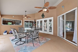 A dining area with a table and chairs, a ceiling fan, and a view through glass doors. - Sea Your Escape | Pool, Game Room & Lanai | Palm Coast Near Flagler Beach (Palm Coast)