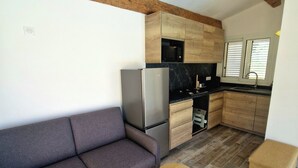Eine kleine Küche mit Holzausstattung, einer eingebauten Mikrowelle und einem Kühlschrank.