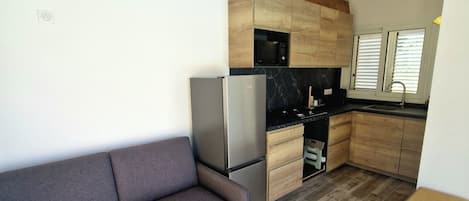 Eine kleine Küche mit Holzausstattung, einer eingebauten Mikrowelle und einem Kühlschrank.