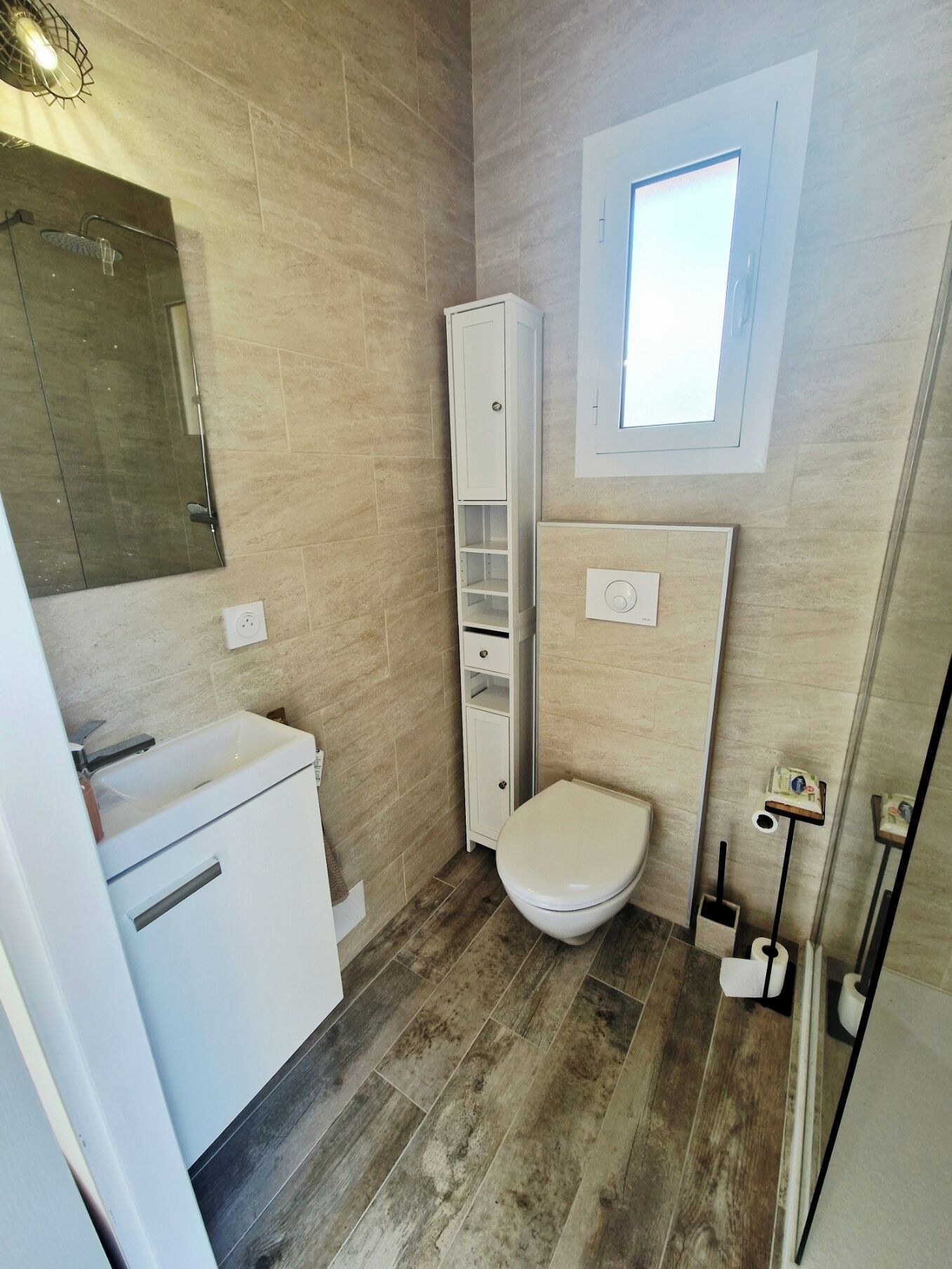 Une petite salle de bain comprenant des toilettes, un meuble et un miroir.