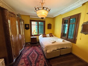 A room with a bed, a wooden wardrobe, a rug, a nightstand, and a hanging light fixture.
