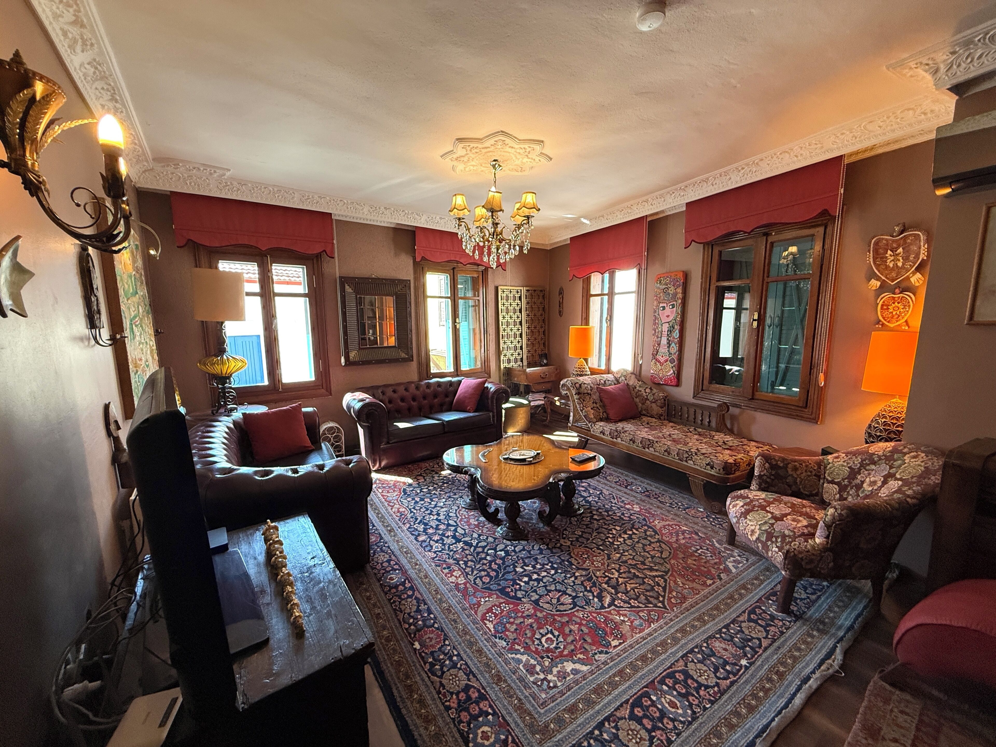 A traditional living room with a patterned rug, leather sofas, and a chandelier.