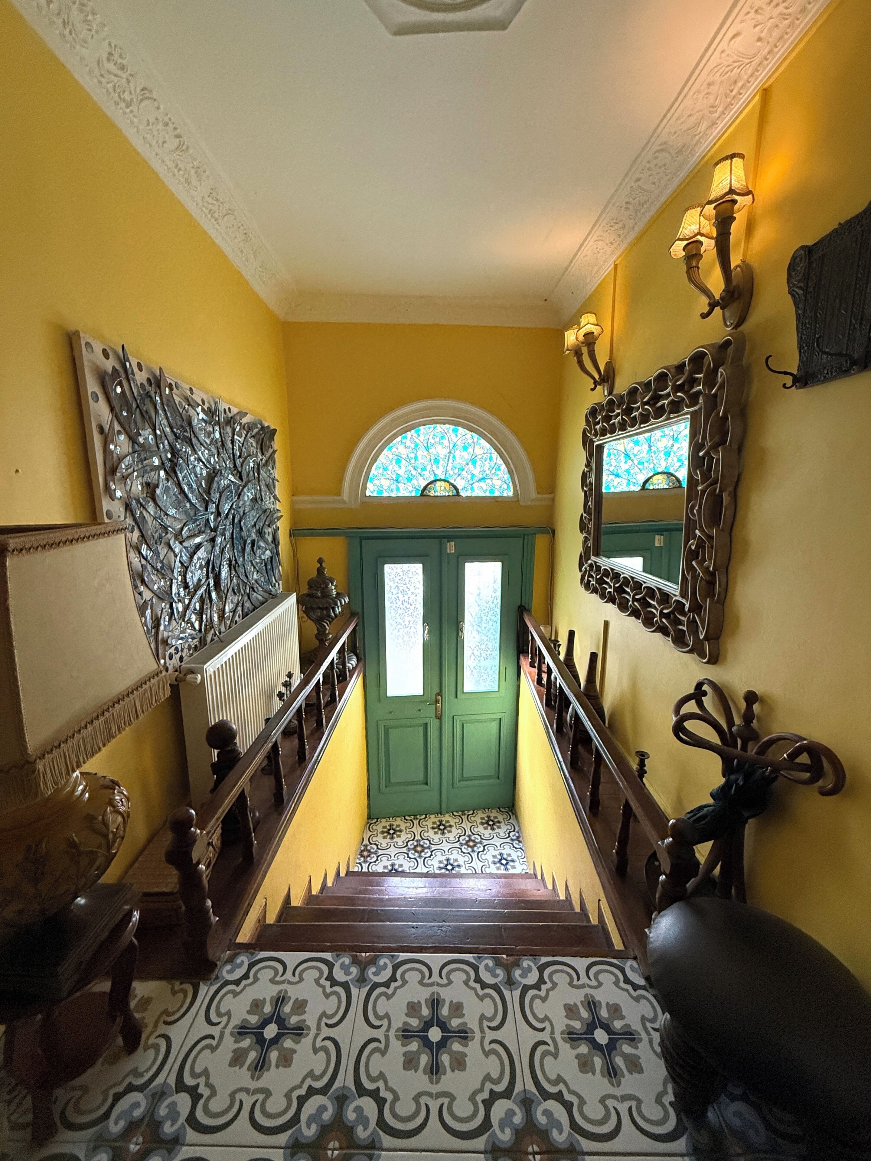 Un escalier dont les marches sont décorées d’un motif particulier, menant à une porte verte dotée de panneaux de verre.