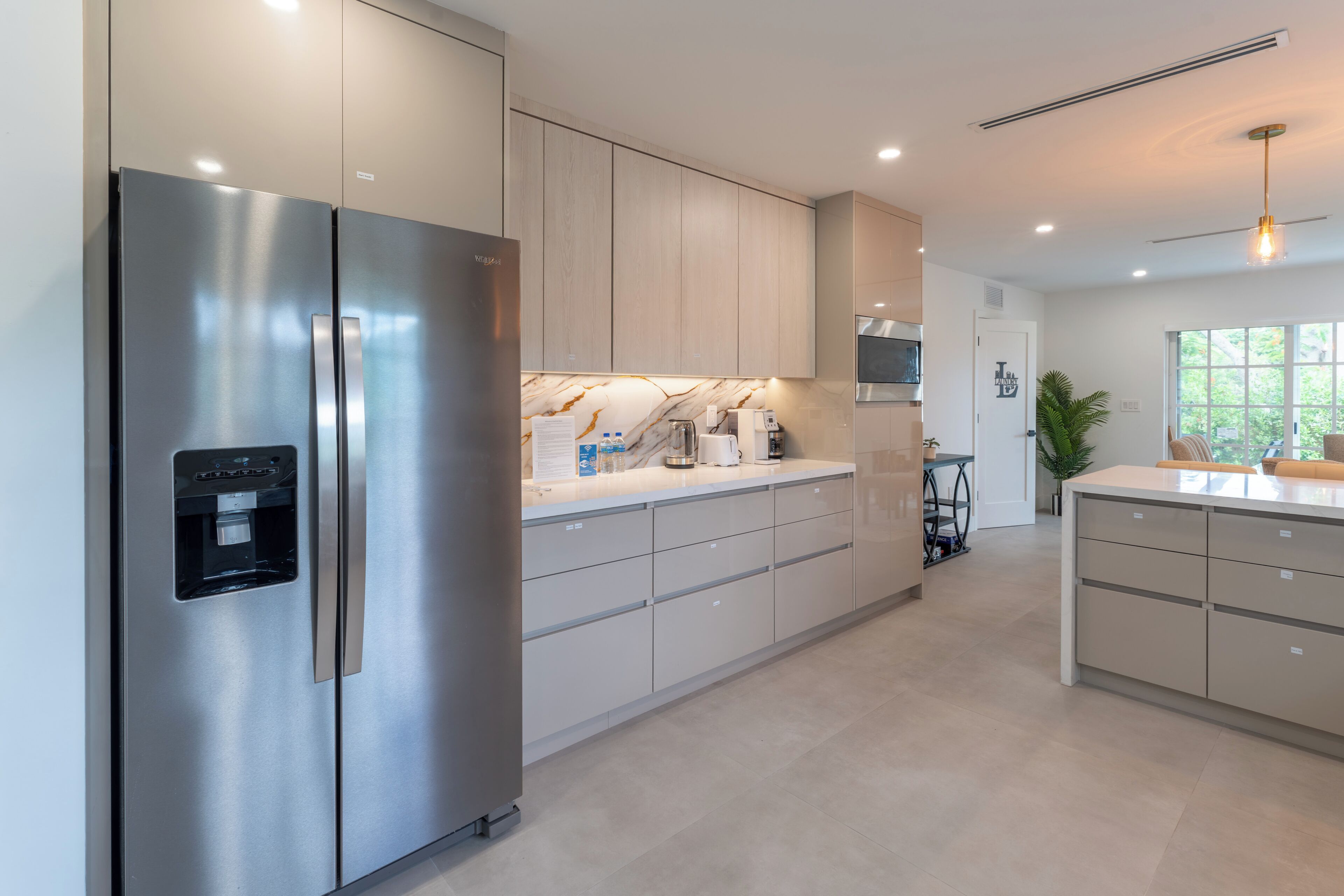 Een moderne keuken met roestvrijstalen apparatuur, een waterdispenser en een marmeren aanrecht.