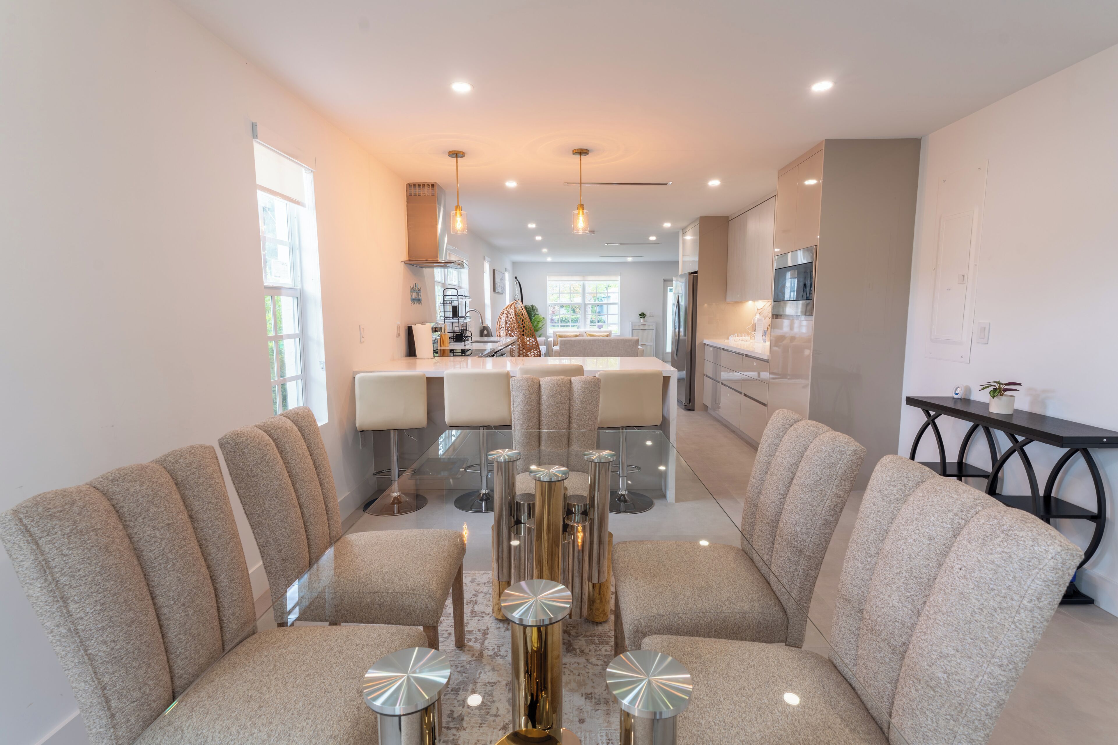A modern living room with a central coffee table, seating area, and a view into the kitchen.