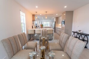 A modern living room with a central coffee table, seating area, and a view into the kitchen. - NEW 3BR • 7 Beds • Sleeps 12+ • Free Parking (West Palm Beach)