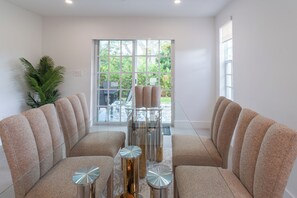 A modern living room with a sofa set, a glass coffee table, and a view of a garden through large windows. - NEW 3BR • 7 Beds • Sleeps 12+ • Free Parking (West Palm Beach)
