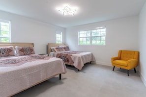 A bedroom with two beds, a yellow armchair, and large windows. - NEW 3BR • 7 Beds • Sleeps 12+ • Free Parking (West Palm Beach)
