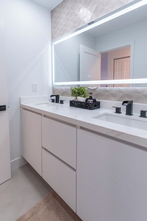 Une salle de bain moderne avec un grand miroir, deux lavabos et un meuble intégré.